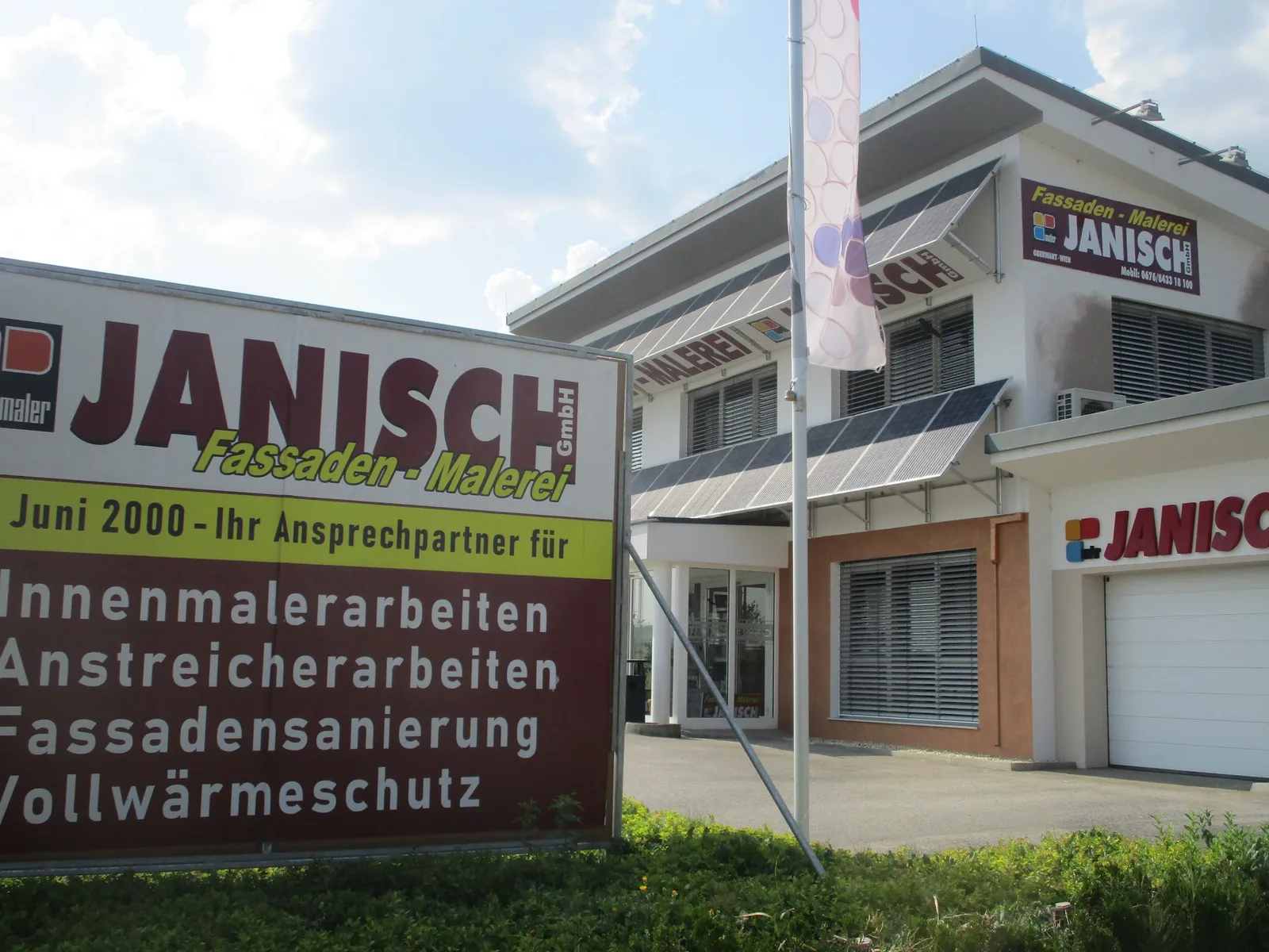 Betriebsgebäude der Malerei Janisch mit beschrifteter Leistungstafel